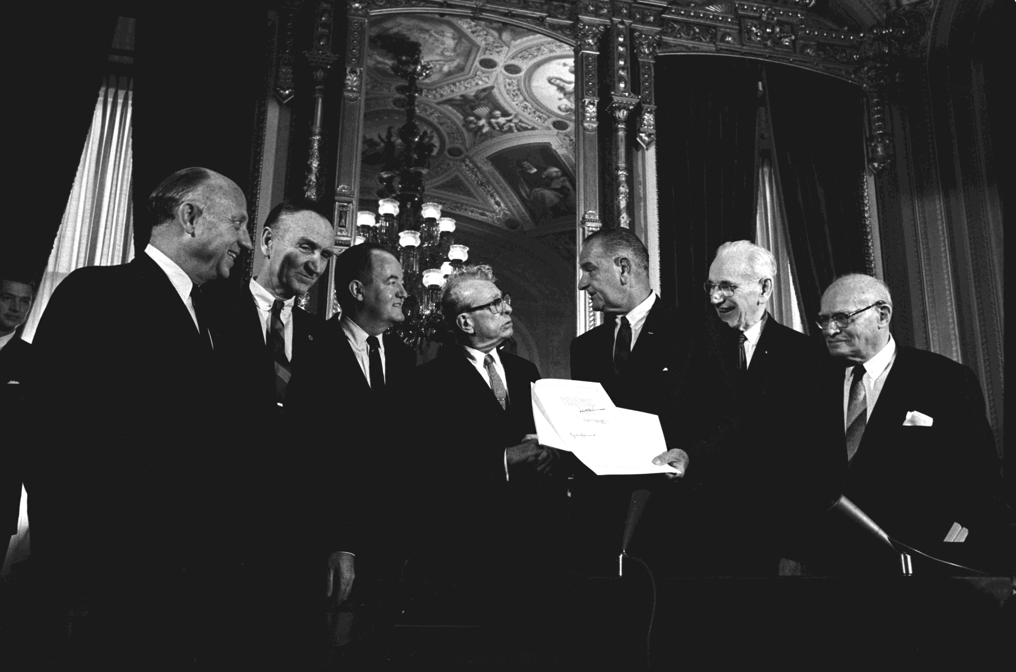 Posing for camera with the signed bill (L-R) Sen. Jacob Javits, Sen. Mike Mansfield, V.P. Hubert Humphrey, Sen. Everett Dirksen, President Lyndon B. Johnson, Speaker John McCormack, unidentified.