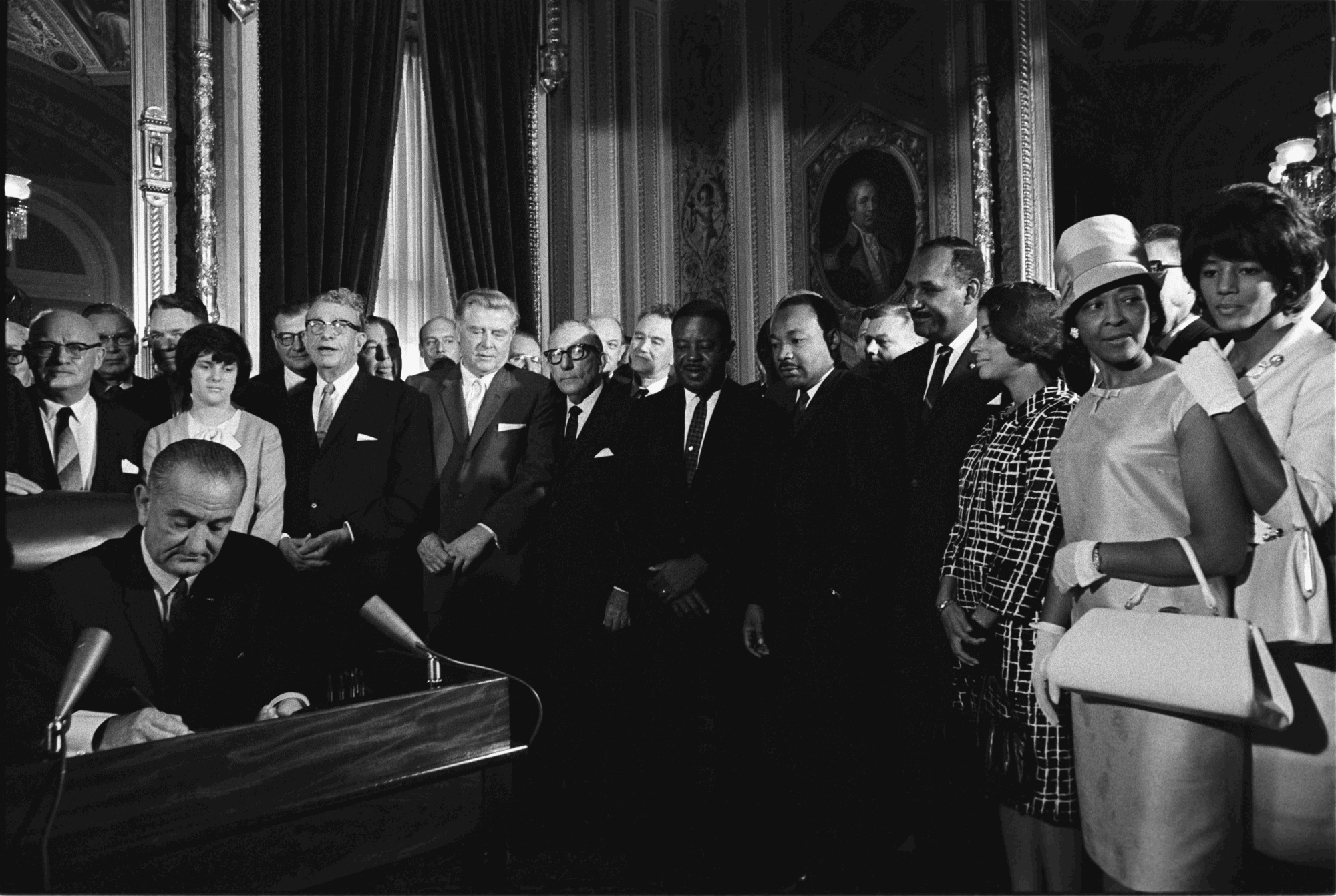 President Lyndon B. Johnson signs the Voting Rights Act as Martin Luther King, Jr. and other civil rights leaders look on.
