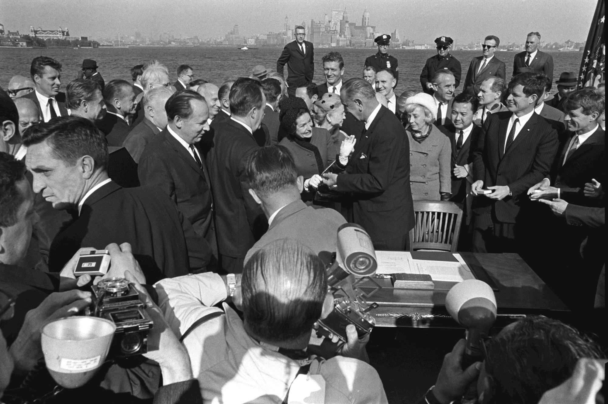 President Lyndon B. Johnson hands Lady Bird Johnson a pen from the signing.