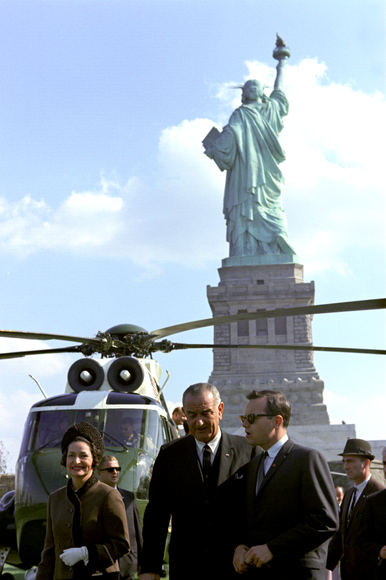 Lady Bird Johnson, President Lyndon B. Johnson, and Press Secretary Bill Moyers make their way to the signing