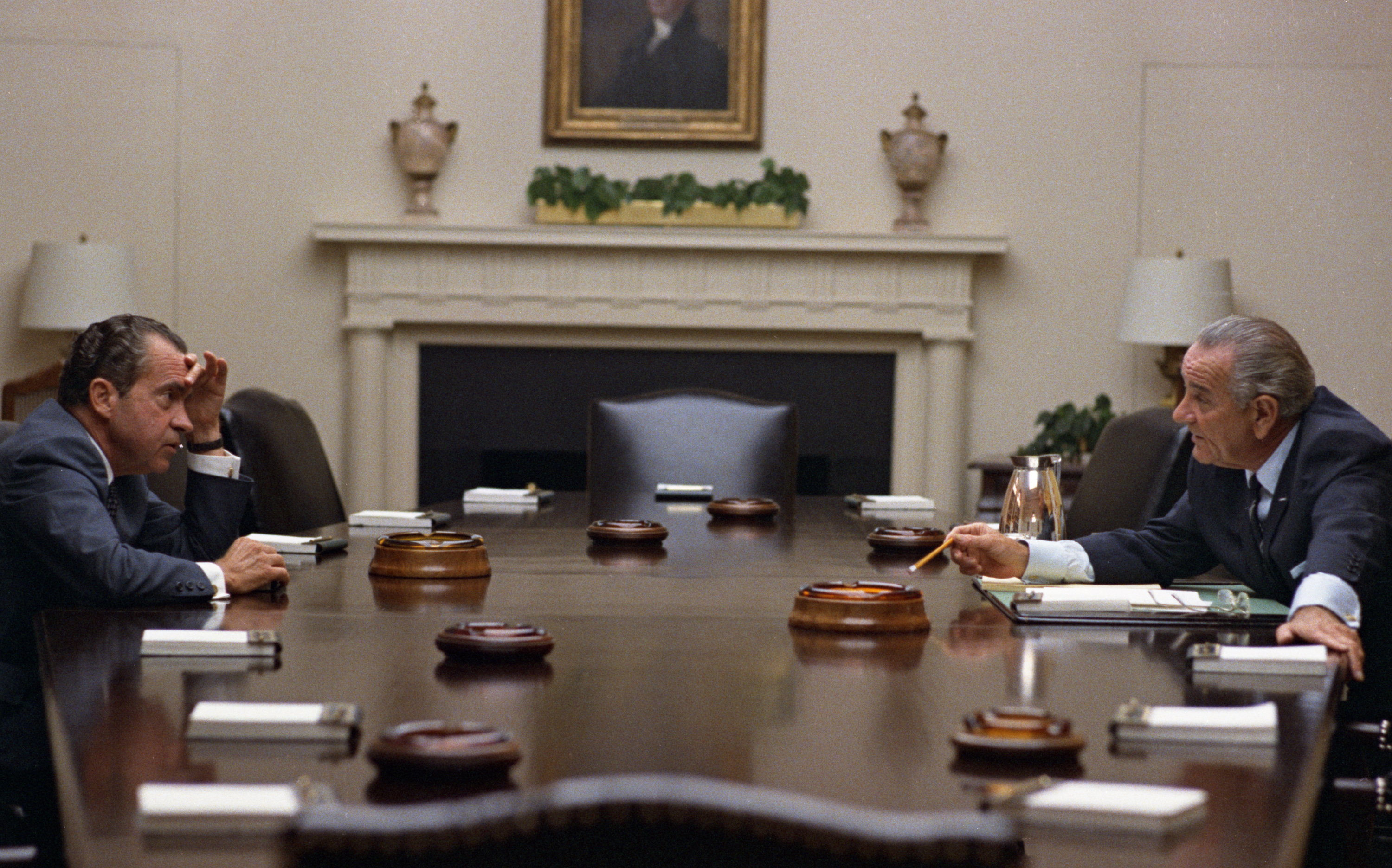 Presidential candidate Richard Nixon (left) and President Lyndon B. Johnson face each other in conversation across the Cabinet Room meeting table.