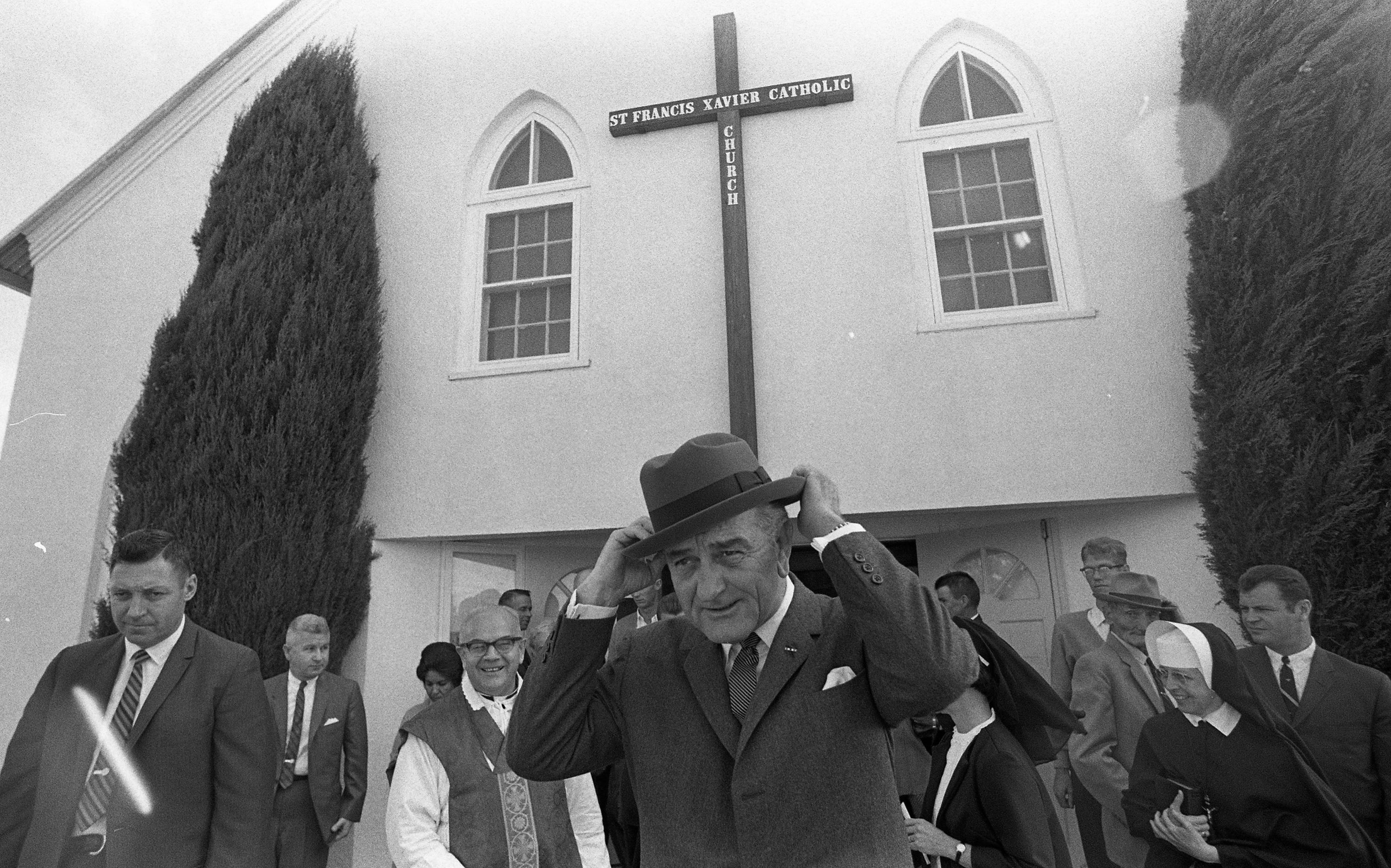 President Johnson adjusts his hat outside of the St. Francis Xavier Catholic Church, in Stonewall, Texas.