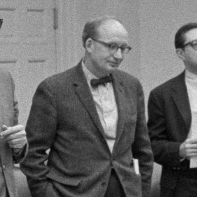 Robert C. Wood stands besides other Cabinet members while President Johnson speaks to them in the Cabinet room.