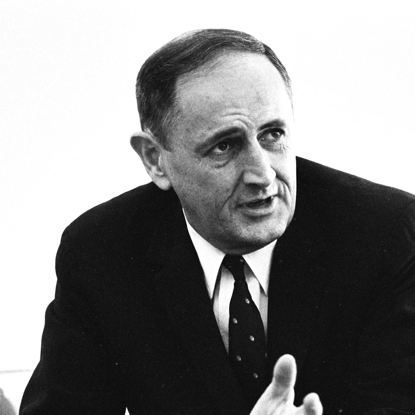 John W. Gardner sitting, hands open in front of him
