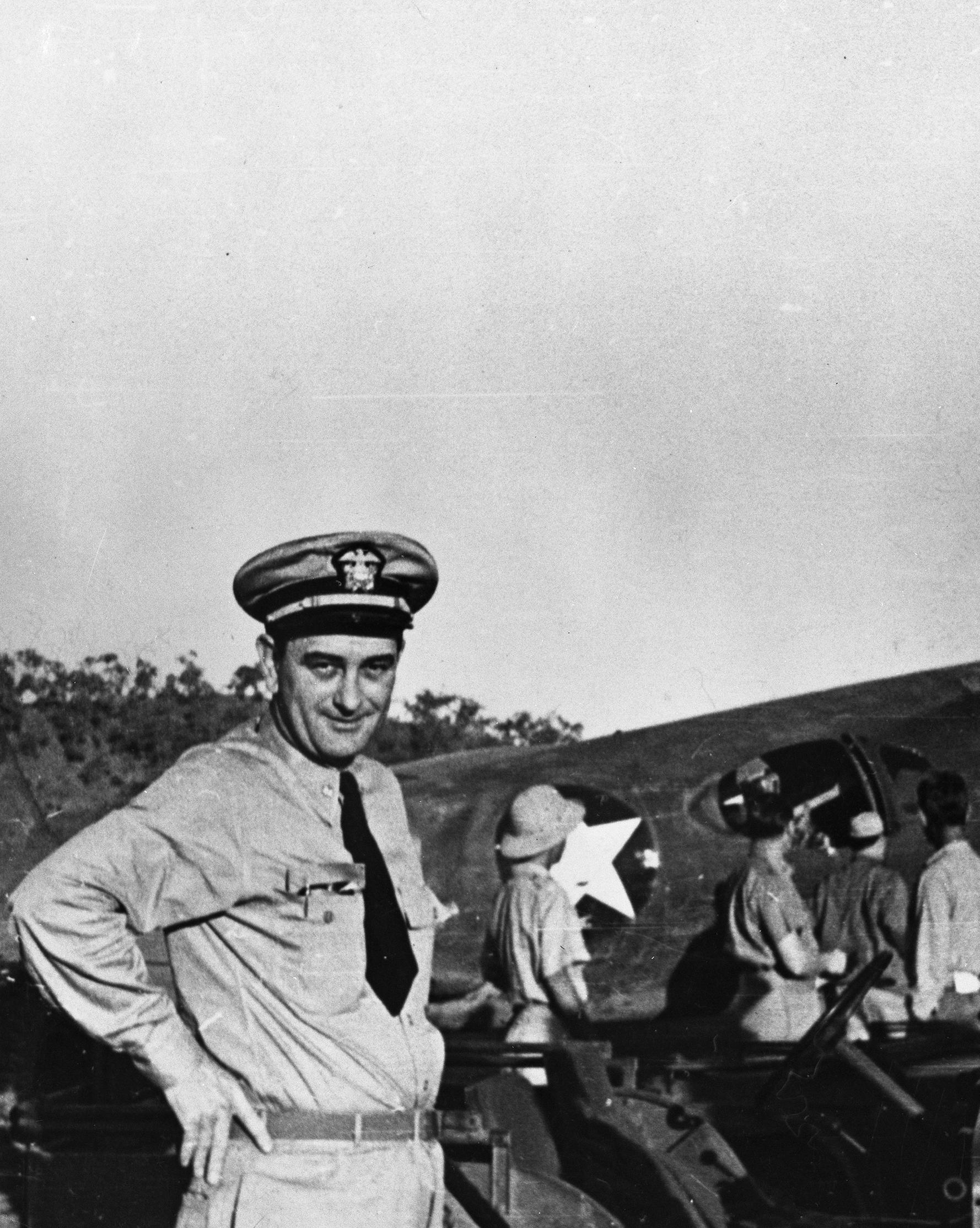 Lt. Commander Lyndon. B Johnson, dressed in his Naval uniform, poses in front of an aircraft at the Seven Mile Air Drome, New Guinea.