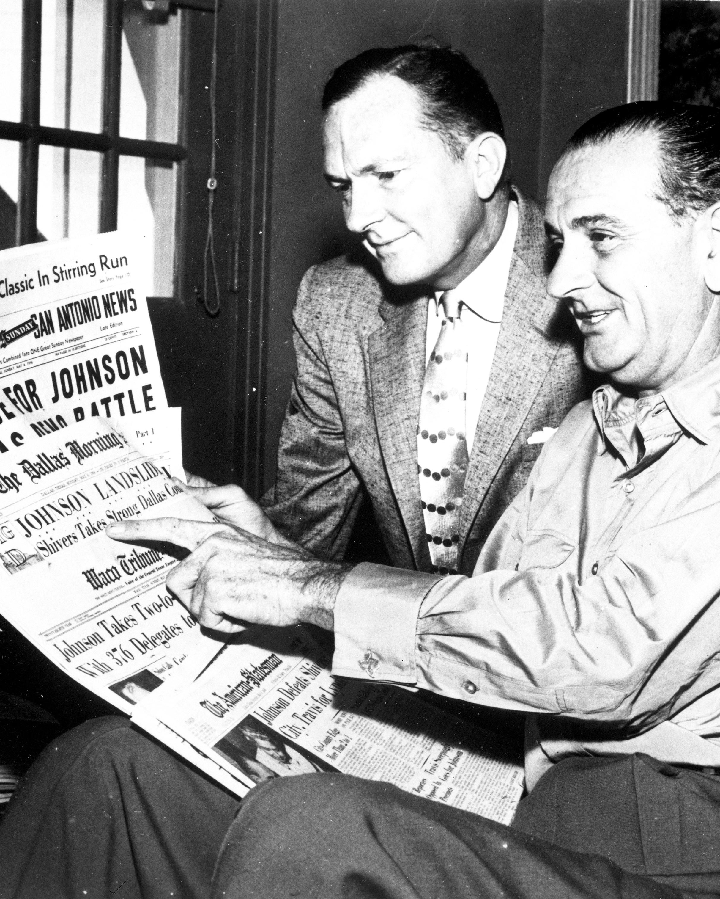 Sen. Lyndon B. Johnson and his brother Sam Houston Johnson look at newspaper headlines proclaiming LBJ's victory. 