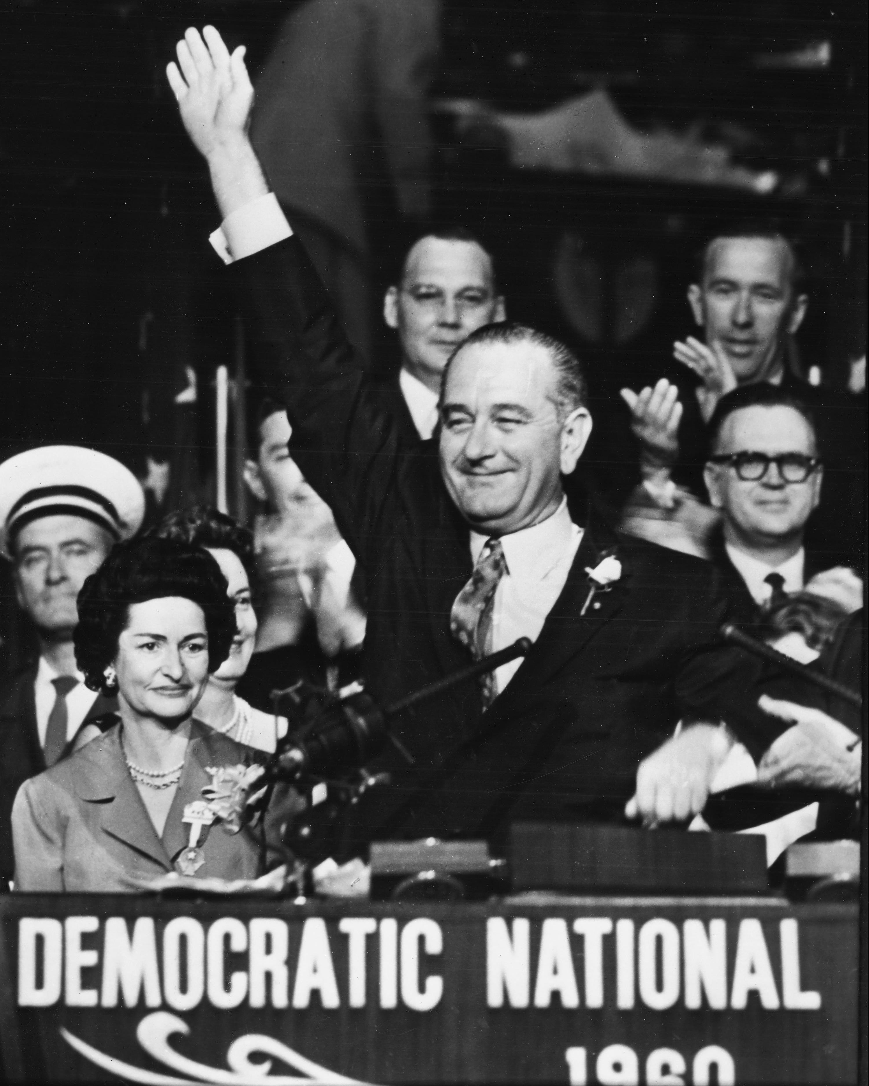 Senator Lyndon B. Johnson waves from the podium, with Lady Bird Johnson smiling by his side, at the Democratic National Convention in Los Angeles California in 1960.
