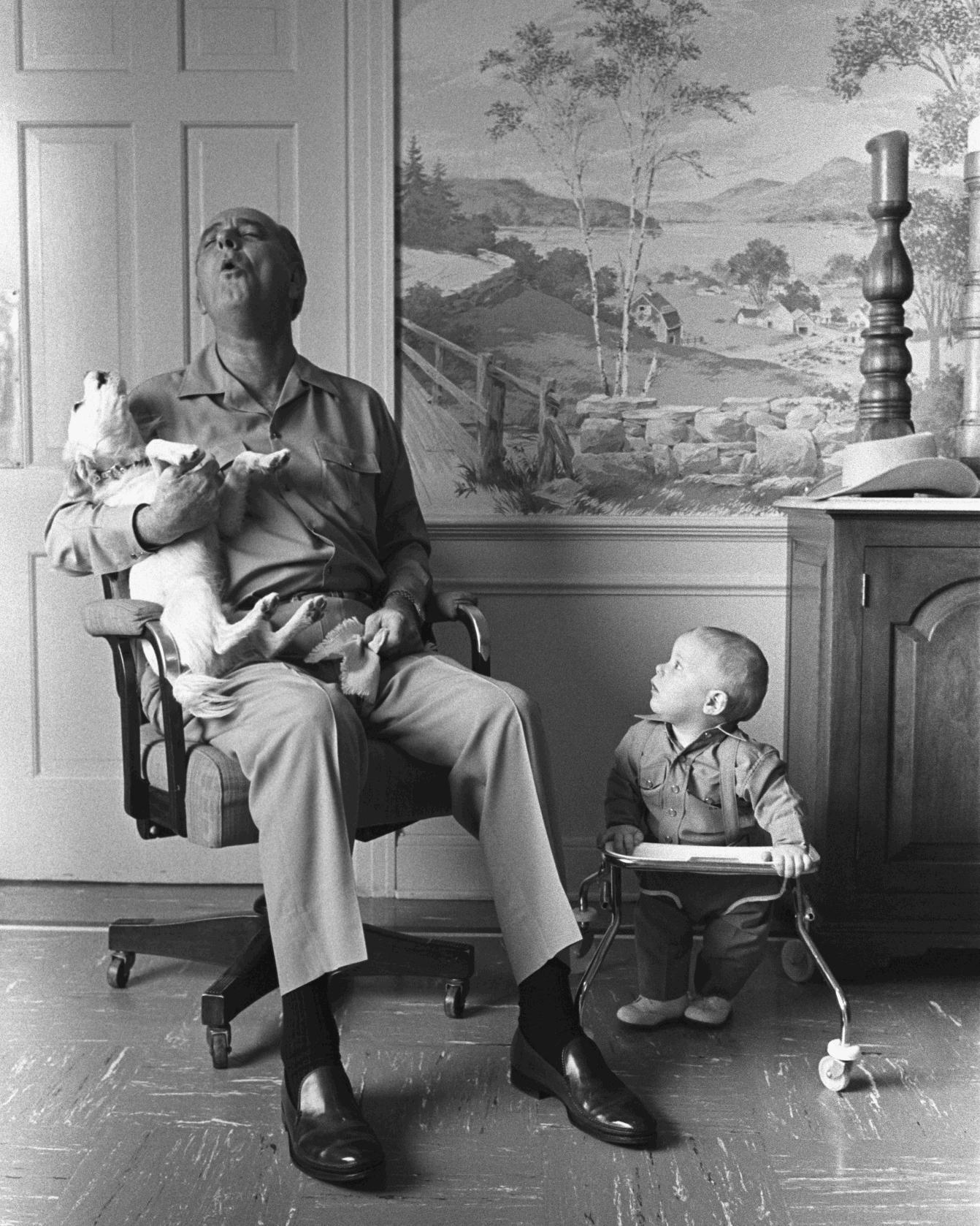 President Johnson, sitting in a chair, sings with his dog, Yuki, while his grandson, Patrick Lyndon Nugent, looks on.