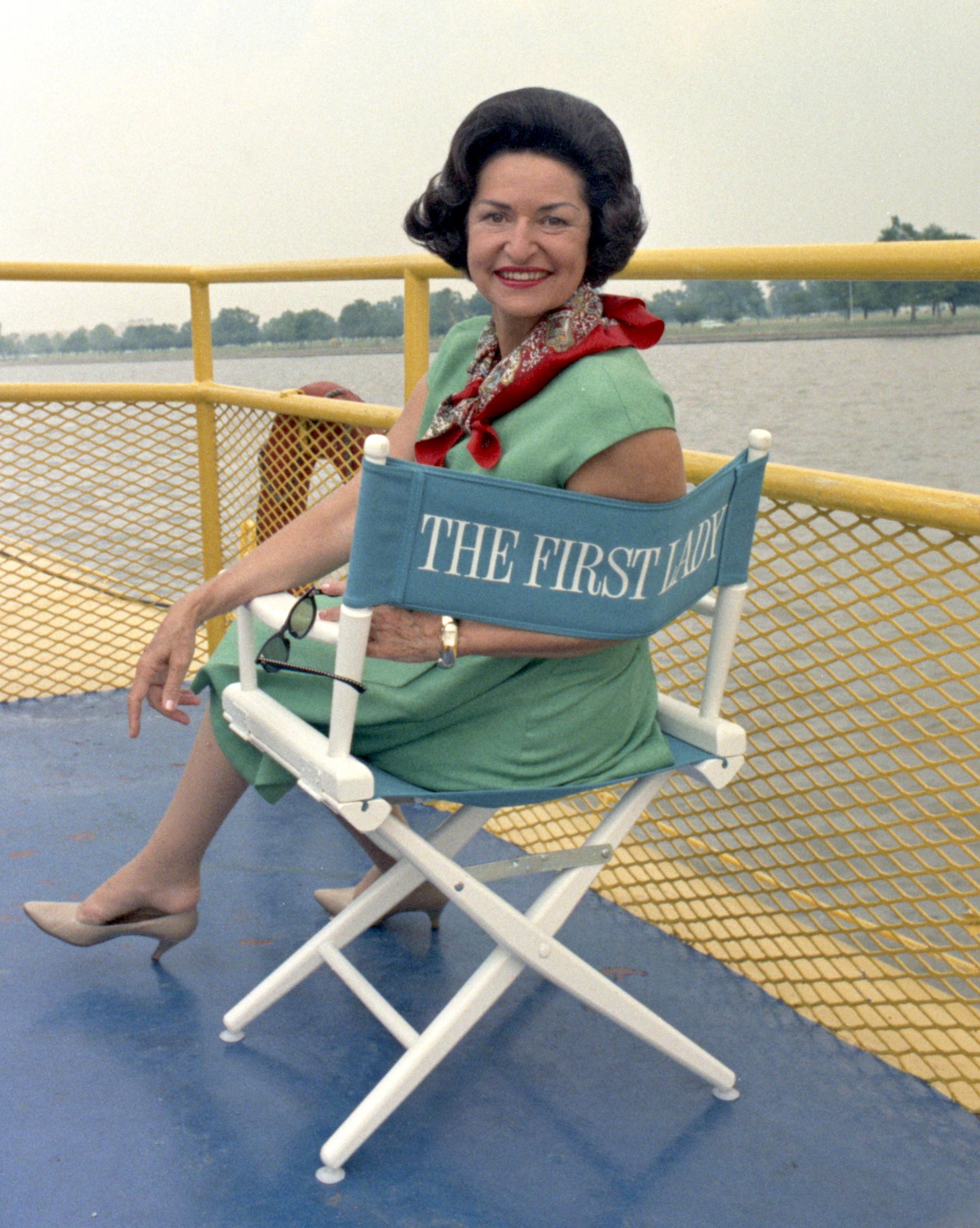 Lady Bird Johnson sits in director's chair.