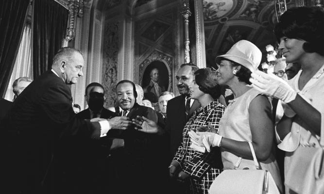 President Lyndon B. Johnson signs the Voting Rights Act as Martin Luther King Jr. and other civil rights leaders look on. LBJ Library photo by Yoichi Okamoto, A1030-8a.