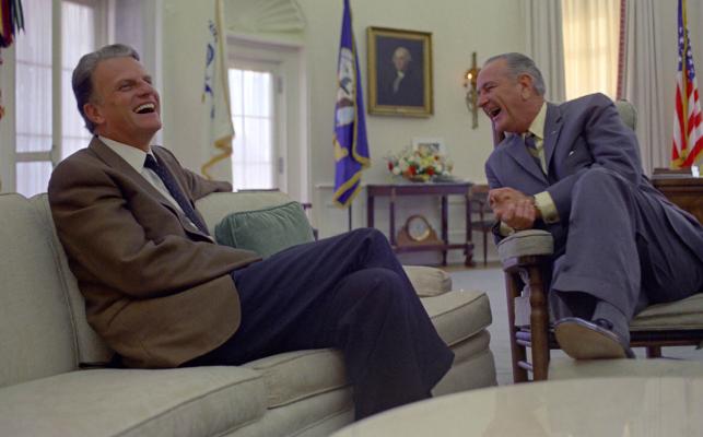 Rev. Billy Graham and President Lyndon B. Johnson share a laugh while meeting in the Oval Office.
