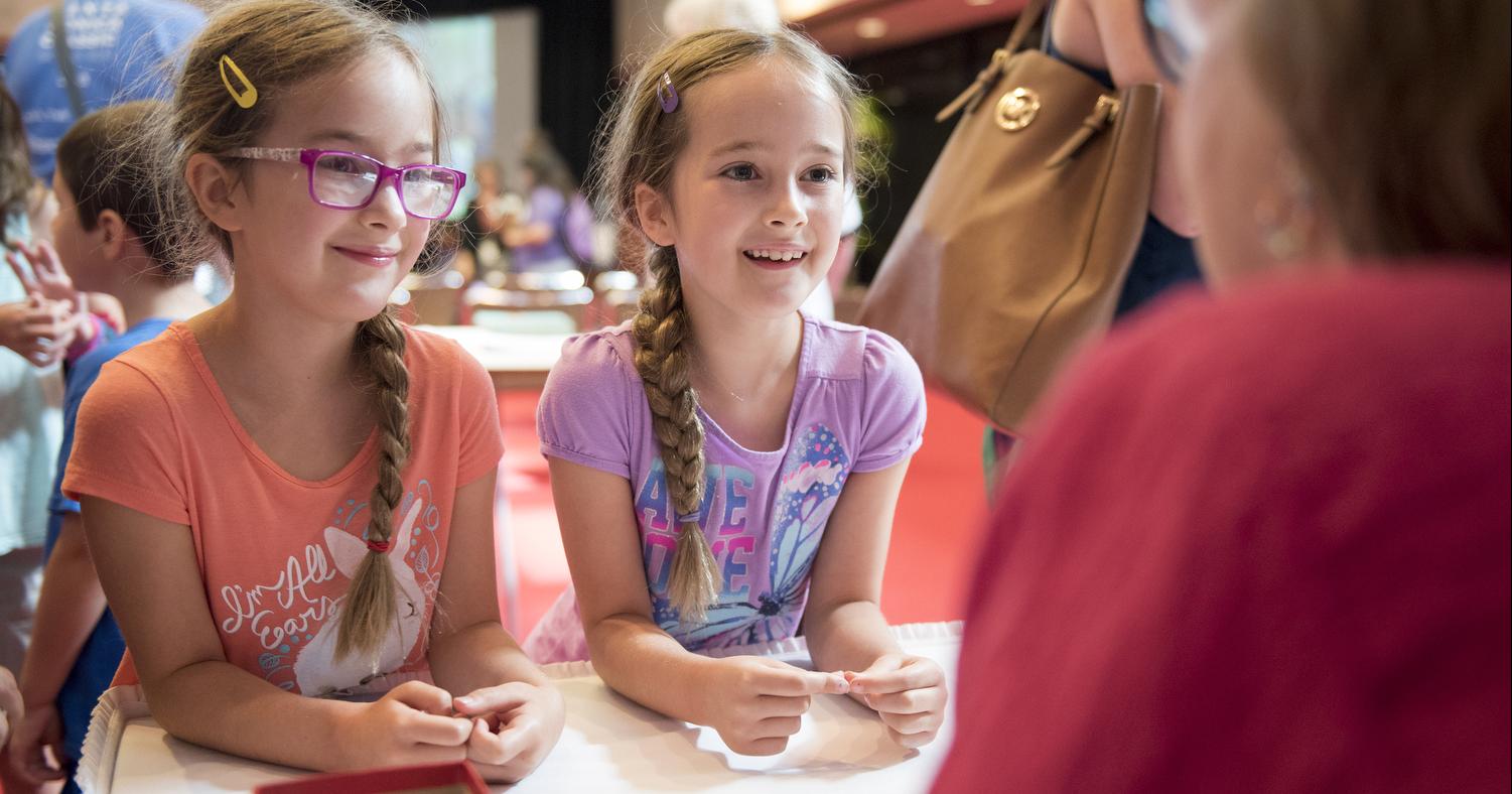 Two young girls smile at author Kathi Appelt while at a summer storytime at the LBJ Library.